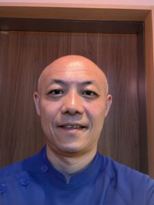 宮崎県都城市「鍼灸治療院たけした」の竹下院長。紺色のスクラブを着用し、微笑む。浅い鍼と刺さない鍼（てい鍼）を用いて自律神経を整える様子。